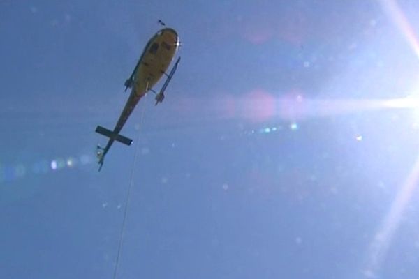 L'hélicoptère multiplie ses rotations au dessus du lac de barrage de Saint-Etienne-Cantalès, dans le Cantal. L'hélitreuillage est la seule solution pour livrer le béton nécessaire à la construction du pont qui va relier les deux rives du plus grand lac artificiel d'Auvergne.