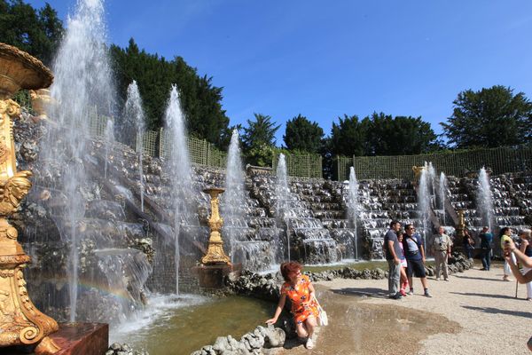 Des touristes se prennent en photo devant les fontaines du Château de Versailles