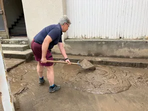 Cette habitante de Thiers nettoie la boue accumulée devantr chez elle. Deux jours après le violent orage qui s'est abattu sur la commune, samedi 20 juillet.