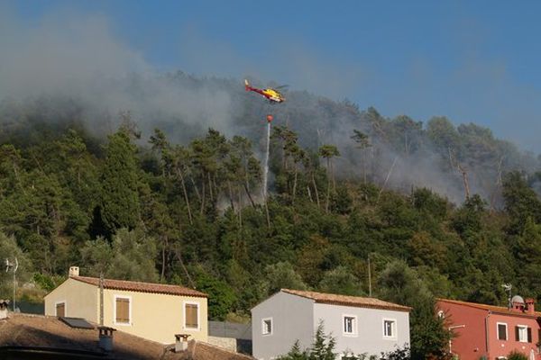 Un bombardier d'eau entrain de larguer pour éteindre les flammes qui menacent les habitations.