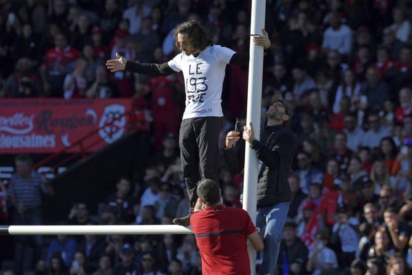 L'un des deux militants de Dernière Rénovation perché sur les poteaux de rugby du stade Ernest wallon.