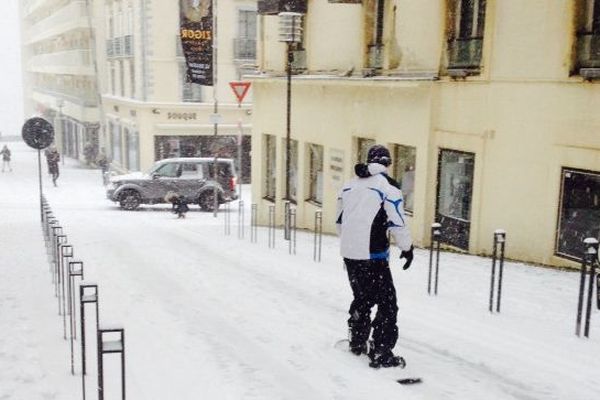 Une jeune homme surfe dans les rues de Biarritz 