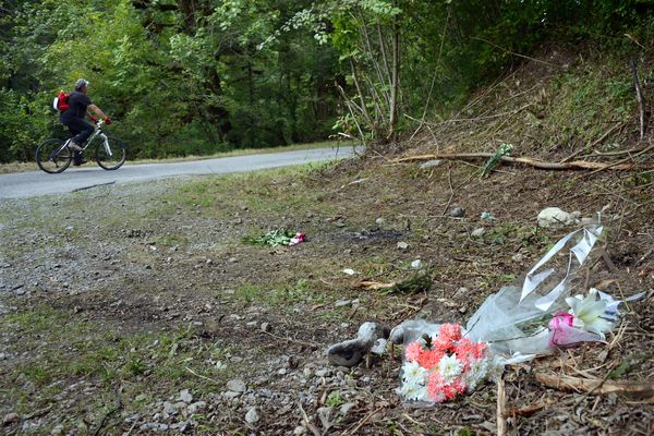 Un cycliste passe devant des fleurs a l'endroit où le 5 septembre 2012 un inconnu tuait 4 membres d'une même famille, des touristes anglais, et un jeune cycliste, sur la route "Combe d'Ire", dans le village de Chevaline en Haute-Savoie.