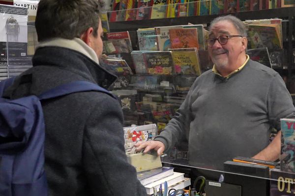 Rolland, passionné de musique et de bandes dessinées, tient la caisse de sa librairie depuis 50 ans.