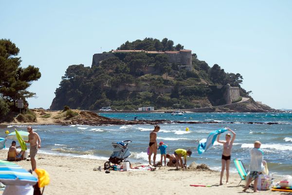 Le fort de Brégançon, dans le Var, et des vacanciers qui se baignent au premier plan.