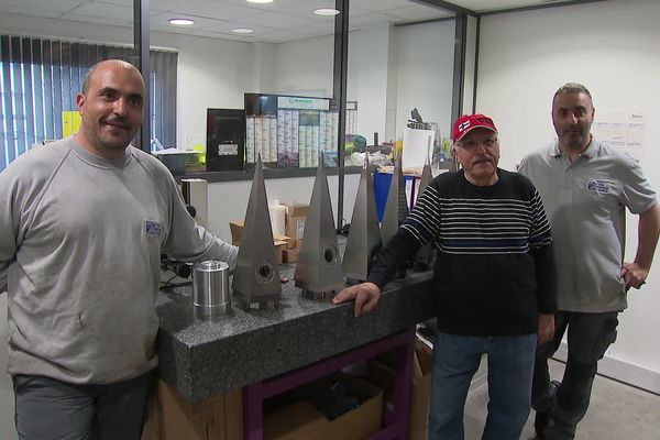 Le père et ses fils posent avec fierté dans leur atelier