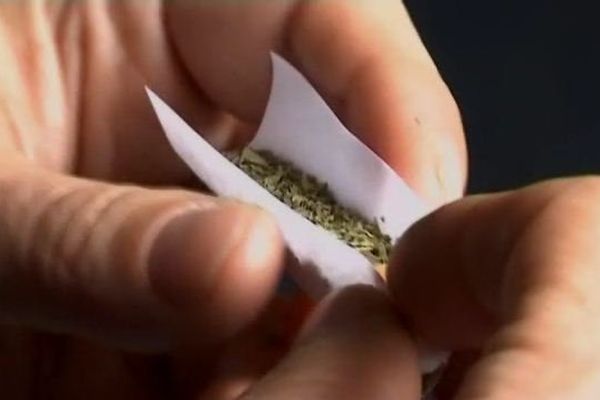 Un adolescent roulant un joint de cannabis. 