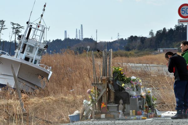 Deux hommes se recueillent aux abords du site de la centrale de Fukushima 