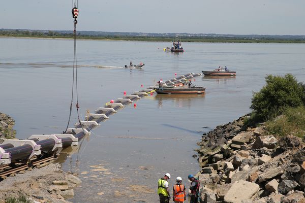 Les fourreaux jumelés descendent sur rail vers la Loire, une fois dans l'eau, les chariots de transports sont retirés par l'homme grenouille puis par la grue.