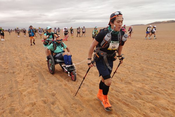 Sofiane Rahmouni installé dans son fauteuil de course, entouré de ses coéquipiers Christopher et Kaïna.