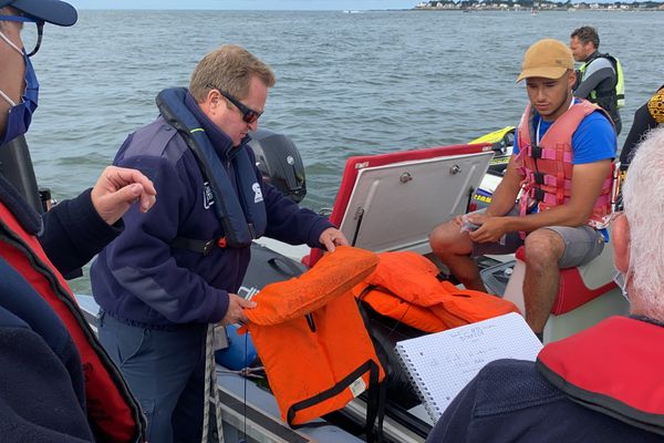 The instructor has put on his life jacket, he must now show his safety equipment.