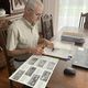 Alain Esquerre dans son salon, feuillette les anciennes revues annuelles de l'institut Notre-Dame de Bétharram où ont été publiées les photos de classe.