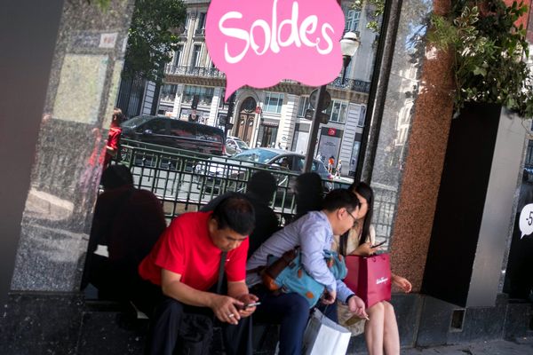 Des clients attendent devant les Galeries Lafayette à Paris.