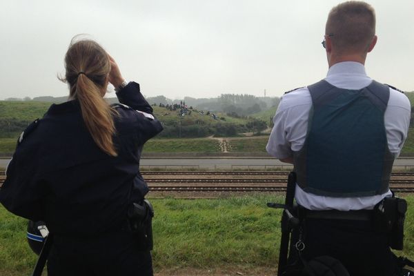 Les policiers surveillent des migrants rassemblés à proximité du port de Calais.