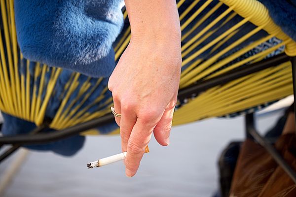 Une femme tient une cigarette en terrasse - Photo d'illustration