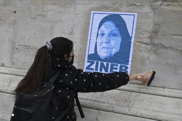 Une jeune femme colle une affiche en hommage à Zineb Redouane, l'octogénaire est décédée à Marseille le 2 décembre 2018 après avoir reçu en plein visage une grenade lacrymogène tirée par la police.