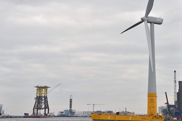 Au premier plan, l'éolienne flottante Floatgen, en arrière plan, la base d'une sous-station de parc éolien construite à Saint-Nazaire