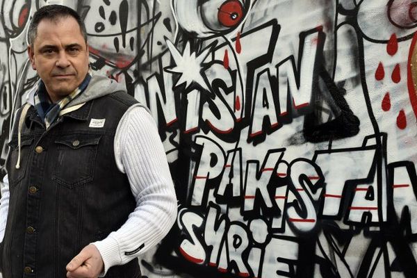 Rob Lawrie, devant une fresque graffée en hommage aux migrants à Paris.