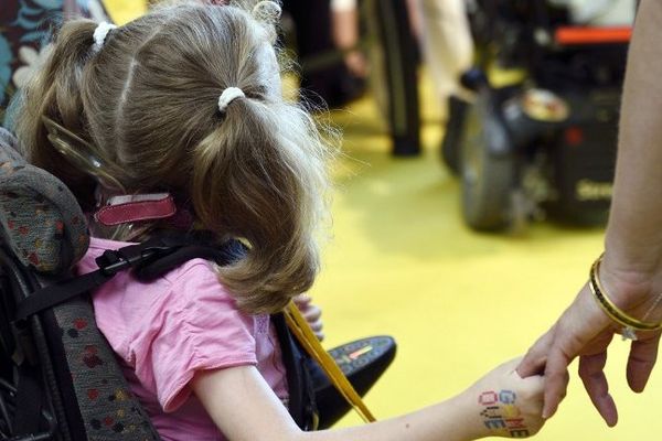 Une petite fille tient la main de sa mère, pendant la campagne de lancement de la 28ème édition du Téléthon, en septembre 2014, à la Cité des Sciences de Paris. 