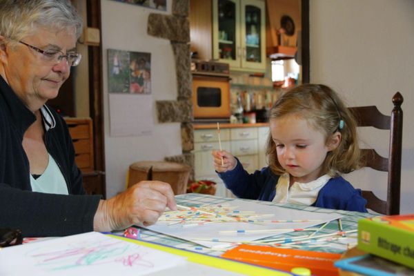 Une grand mère joue au mikado avec sa petite fille.