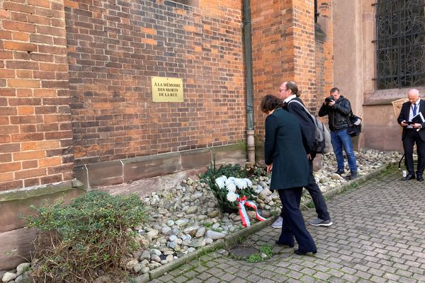 Dépôt de gerbe devant la plaque dédiée aux morts de la rue.