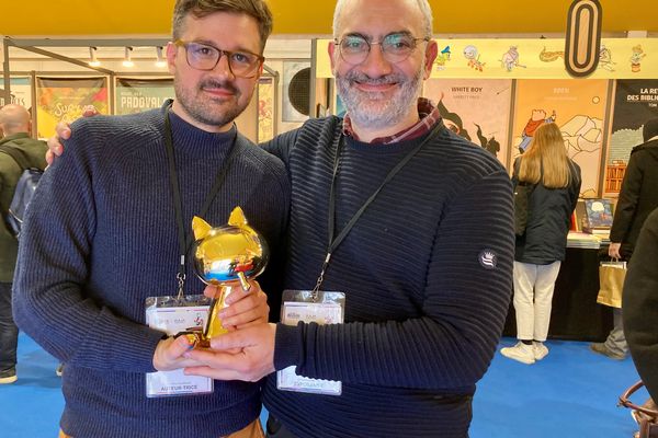 Martin Panchaud, Fauve d'or 2023, pose avec son éditeur Serge Ewenczyk (çà et là) dans les allées de la bulle du Nouveau Monde, dédiée aux éditeurs indépendants, au FIBD d'Angoulême, dimanche 29 janvier 2023.