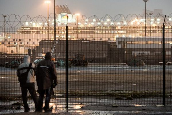 Deux migrants regardent un ferry, dans le port de Calais en octobre 2014