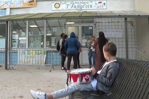 Devant l'école élémentaire Paul Langevin à Gennevilliers, un enfant attend de retrouver un maître d'école tandis que les autres enseignants réclament plus de personnel