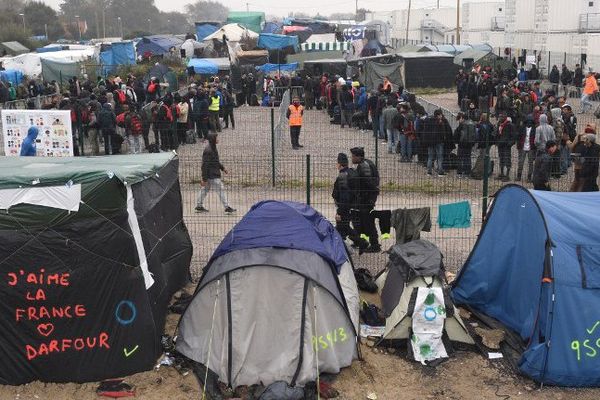 Des migrants font la queue devant un hangar pour ensuite être répartis dans toute la France.