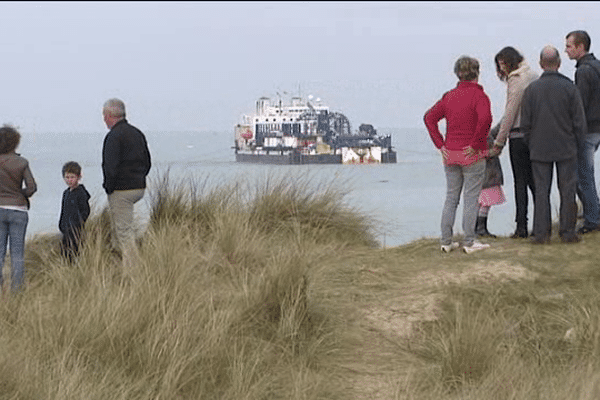 Au loin, depuis la plage d'Armanville, l'embarcation qui déroulera les 34 kilomètres de câbles sous-marins jusqu'à Jersey. 