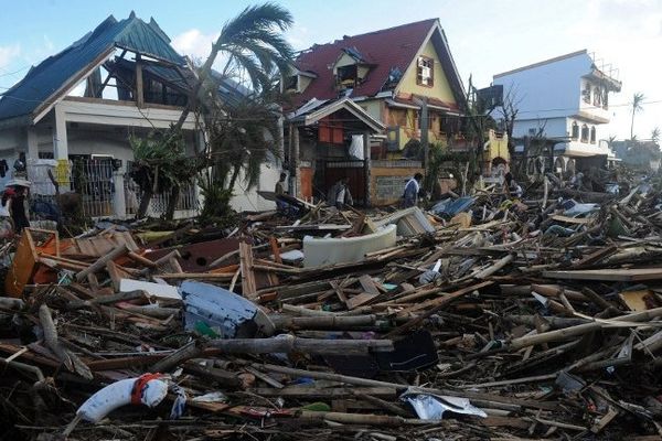 Des habitants marchent au milieu des débris et des maisons détruites à Palo, à l'est de l'île de Leyte, le 10/11/2013, 3 jours après le passage du super typhon Haiyan.