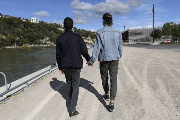 Un couple d'hommes marchant main dans la main sur les rives de Saône à Lyon