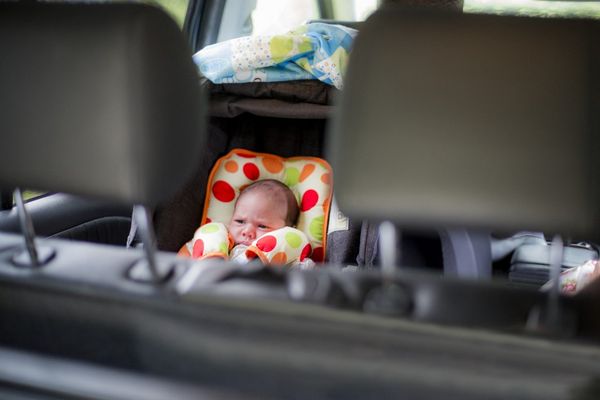 Un bébé installé dans un siège auto d'une voiture.