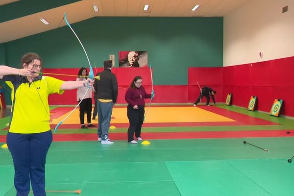 Une femme s'entraîne au tir à l'arc lors d'une séance de sport avec Mobil Sport