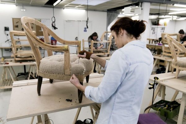 Une jeune apprentie en train de travailler dans un atelier de fabrication de fauteuils.