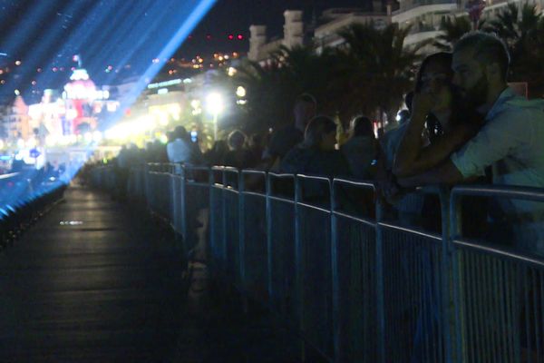 Un couple assiste à la projection des 86 faisceaux lumineux sur les lieux de l'attentat. 