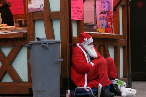 Un SDF en habit de père Noël fait la manche au marché de Noël de Sélestat.