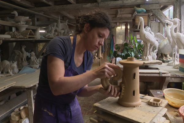 Marie, potière de la Poterie de Bavent, monte l'élément central d'un épi de faitage.