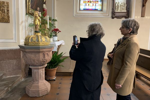 La maire d'Ohnenheim et une bénévole en train de prendre en photo les fonds baptismaux qui font partie des objets protégés de leur commune