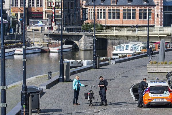 Des policiers belges verbalisent une femme à Gand, le 27 mars.