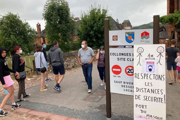 Des panneaux artisanaux annoncent l'obligation de porter le masque dès l'entrée dans le village de Collonges-la-Rouge