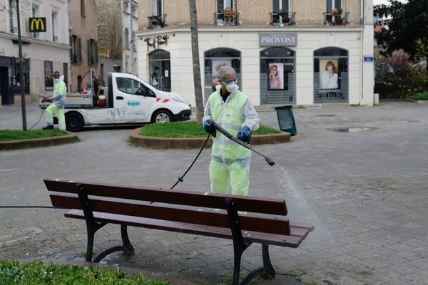 Un agent de la propreté désinfecte un banc à Suresnes (Hauts-de-Seine).