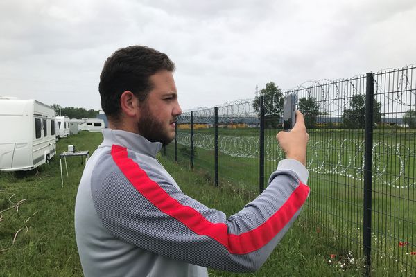 La clôture, équipée de barbelés, sépare l'aire de gens du voyage d'une zone d'activité. Des entreprises voisines ont demandé cette délimitation pour réduire les intrusions.