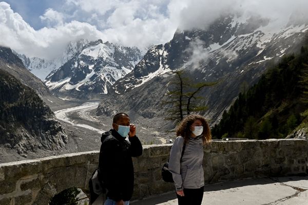 Des touristes portent le masque devant la Mer de glace dans le massif du Mont-Blanc, le 16 mai 2020. 