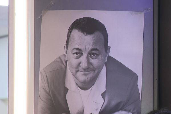 Le visage de Coluche aposé à proximité d'une collecte des Restos du Coeur.