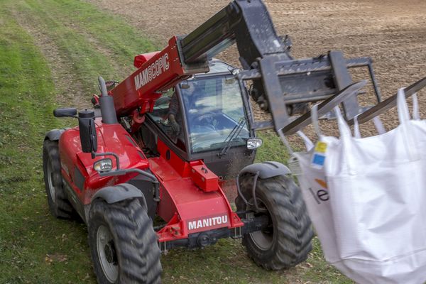 Une chargeuse téléscopique Manitou manipulant un sac de semences.