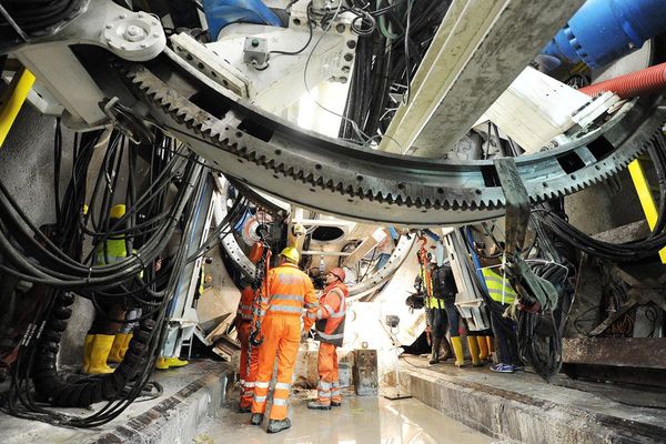 Des ouvriers sur le chantier de construction du futur TGV Lyon-Turin devant le grand tunnelier TBM utilisé pour l'excavation du tunnel de la ligne ferroviaire.