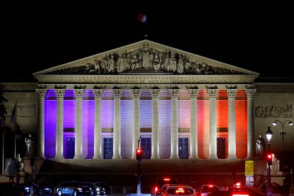 La façade du Palais Bourbon, à Paris, illuminée aux couleurs de la nation pour rendre hommage à l'enseignant assassiné et aux deux blessés lors de l'attentat dans un lycée d'Arras.