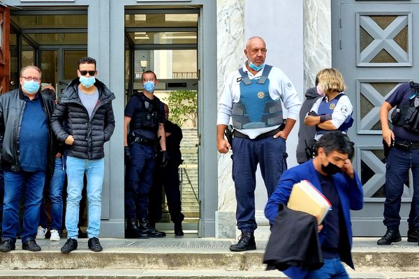 Filippo de Carlo (lunettes de soleil), à la sortie du palais de justice de Bastia, entouré de plusieurs policiers chargés d'éviter des heurts avec les proches du prévenu.