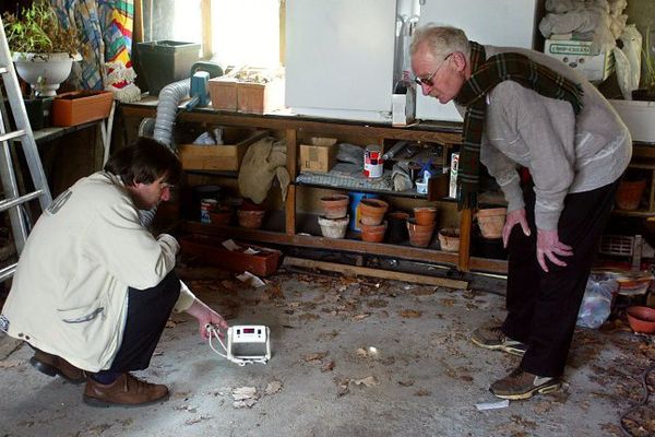 Un technicien (G) de la Commission de recherche et d'information indépendante sur la radioactivité (CRIIRAD) mesure, le 01 avril 2003, les seuils de radon (un gaz invisible émis par le radium) dans la cave du pavillon d'un monsieur, en région parisienne.